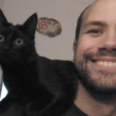Dani smiling beside his black cat